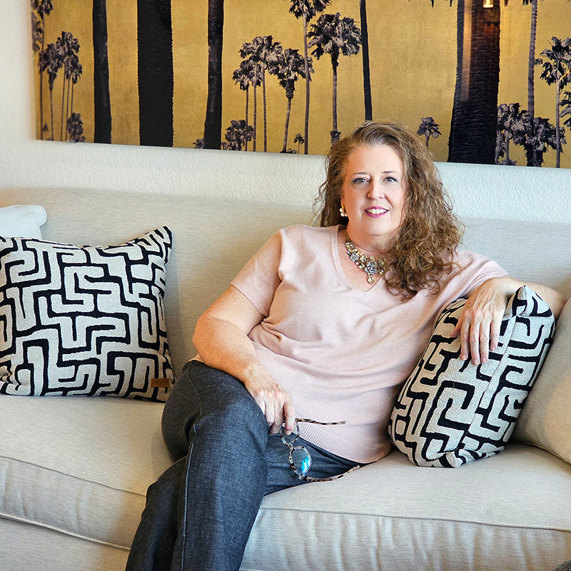 Christina-Rodriguez-interior-desginer-in-league-city-tx-Diva-by-Design Interior designer Christina Rodriguez seated on a white sofa in a neutral, contemporary beach condo she designed in South Padre Island TX