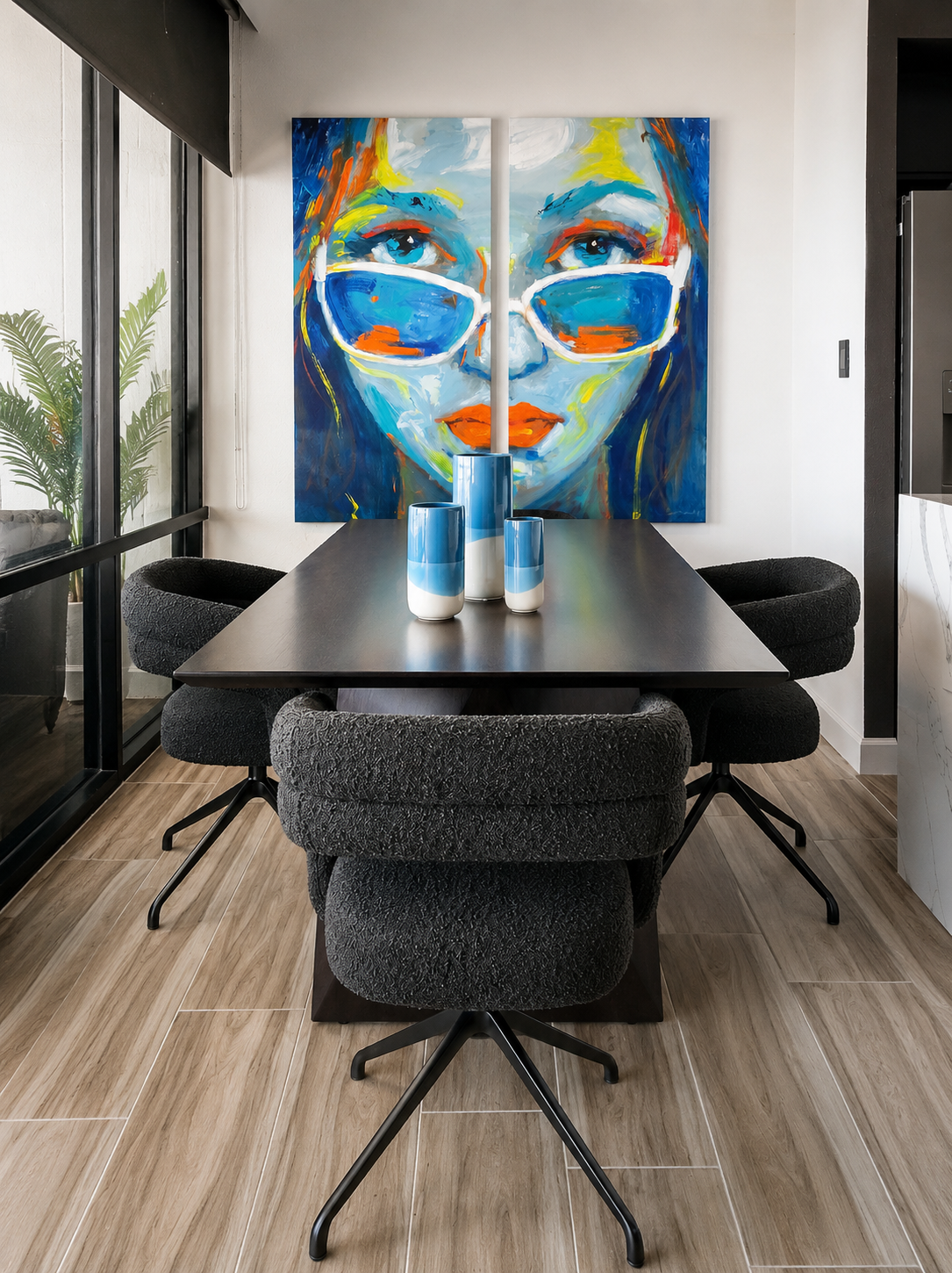 Modern dining area with a black dining table, textured charcoal swivel chairs, colorful contemporary portrait artwork, floor-to-ceiling windows, and luxury coastal condominium interior design