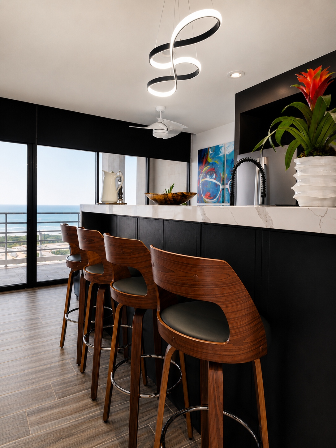 Modern coastal condo wet bar with walnut bar stools, black cabinetry, white quartz countertop, sculptural pendant lighting, and ocean views through floor-to-ceiling windows